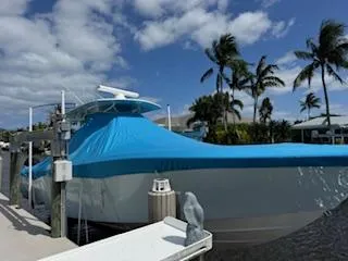 Reel Craft Yacht Photos Pics 2024 SeaVee 340Z boat docked, covered in blue tarp, with palm trees in the background.