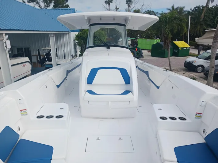  Yacht Photos Pics 2024 Intrepid 375 Nomad SE boat with blue and white seating, docked near palm trees.