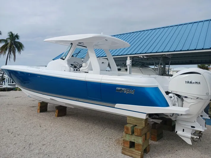  Yacht Photos Pics 2024 Intrepid 375 Nomad SE boat with blue hull, displayed on wooden blocks.