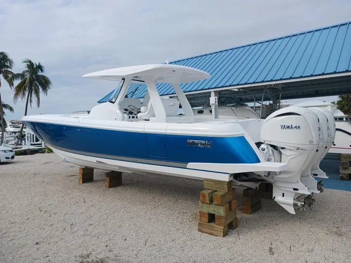  Yacht Photos Pics 2024 Intrepid 375 Nomad SE boat with blue hull, displayed on blocks, near palm trees.
