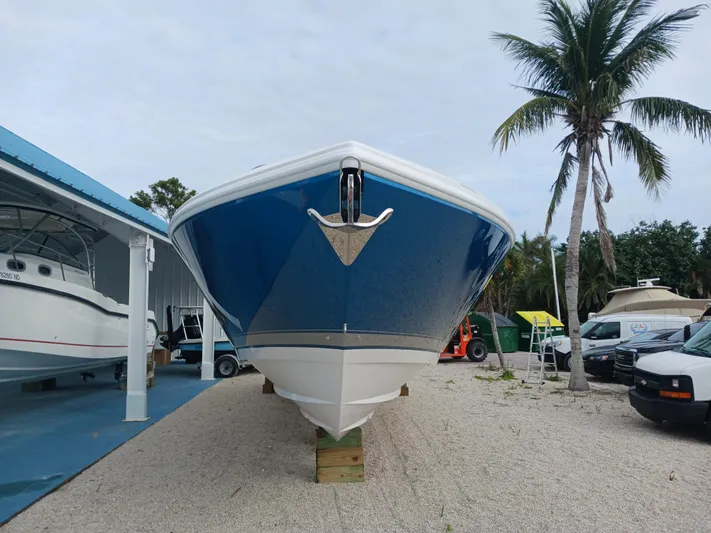  Yacht Photos Pics 2024 Intrepid 375 Nomad SE boat displayed outdoors, front view, with palm trees and vehicles nearby.