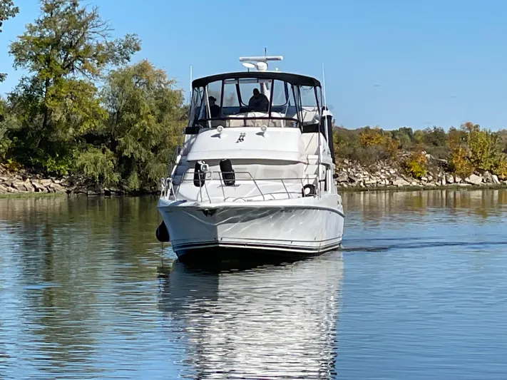 Yacht Photos Pics 1999 Silverton 392 Motor Yacht cruising on a calm river with trees in the background.