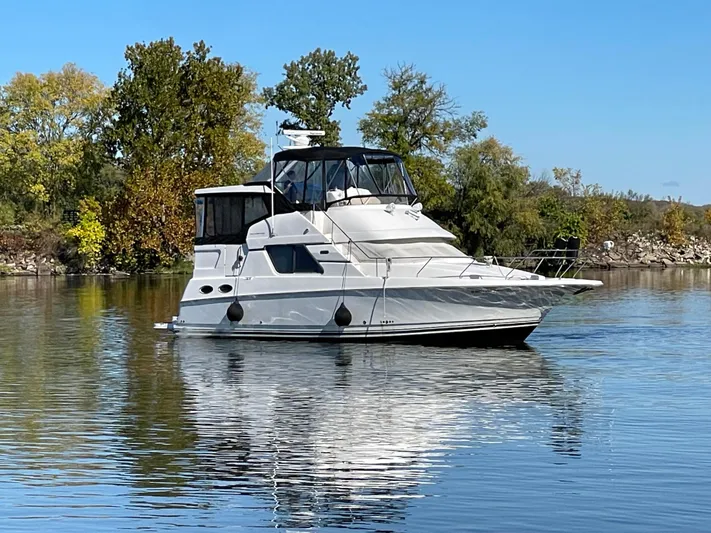  Yacht Photos Pics 1999 Silverton 392 Motor Yacht on calm water, surrounded by trees under a clear blue sky.