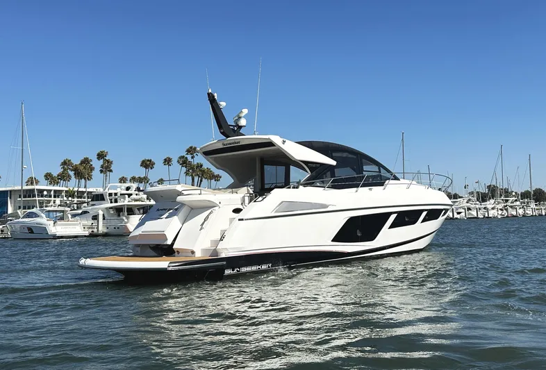 Forever Young Yacht Photos Pics 2019 Sunseeker Predator 57 yacht cruising in a marina with palm trees and clear skies.