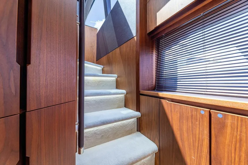  Yacht Photos Pics Interior staircase of 2019 Galeon 640 Fly yacht with wooden paneling and carpeted steps.
