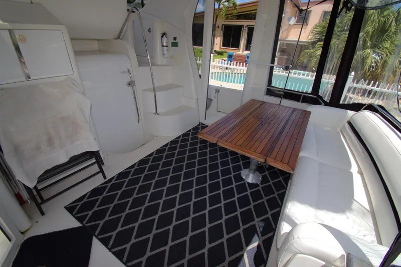 IV Play Too Yacht Photos Pics 2005 Carver 444 Cockpit Motor Yacht interior with seating, wooden table, and patterned rug.