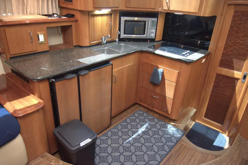 IV Play Too Yacht Photos Pics 2005 Carver 444 Cockpit Motor Yacht kitchen with wood cabinetry, granite countertops, and modern appliances.