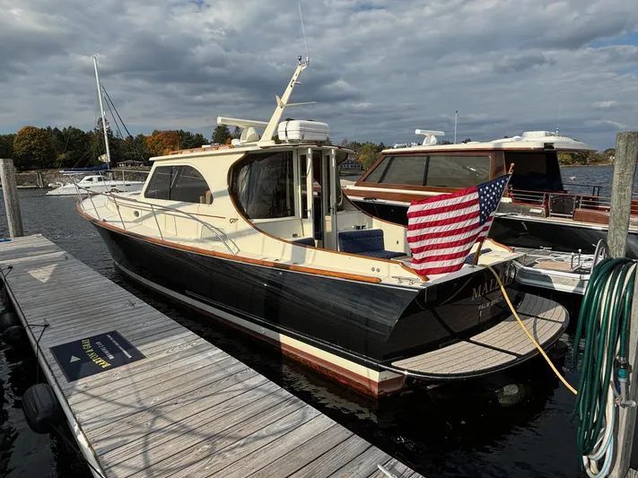 Mallard Yacht Photos Pics Hinckley Talaria 44 MY 2005 yacht docked, displaying an American flag, under a cloudy sky.