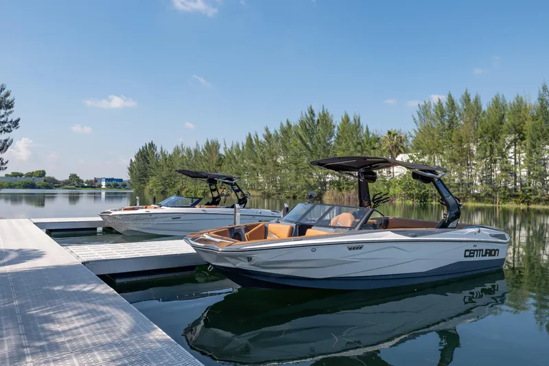  Yacht Photos Pics 2025 Centurion Nv233 boats docked on a serene lake under a clear blue sky.
