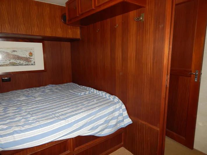 Yacht Photos Pics Cozy bedroom interior of 1981 Hatteras 50 Convertible yacht with wood paneling and striped bedding.