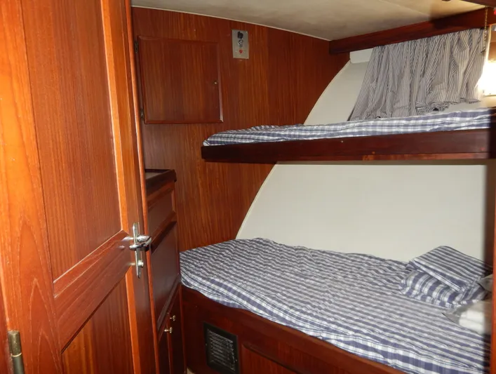  Yacht Photos Pics Interior of 1981 Hatteras 50 Convertible with wooden bunk beds and striped bedding.