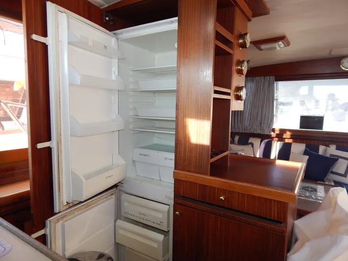  Yacht Photos Pics 1981 Hatteras 50 Convertible yacht interior with open refrigerator and wooden cabinetry.