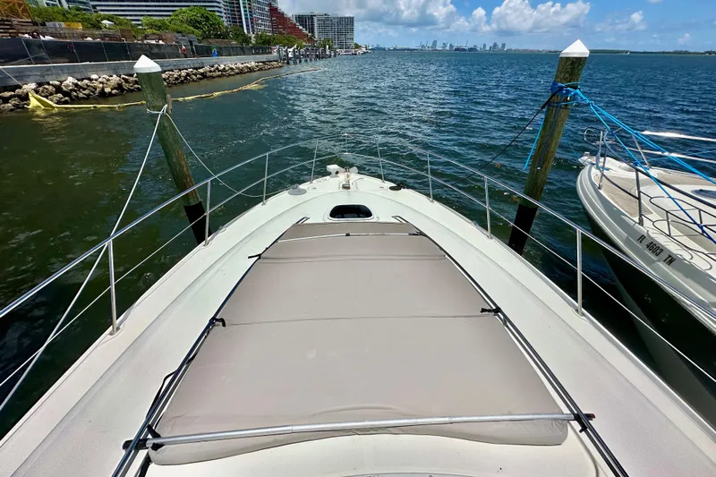 Tsuki Yacht Photos Pics 2005 Sea Ray 48 Sundancer yacht docked by waterfront with city skyline in background.