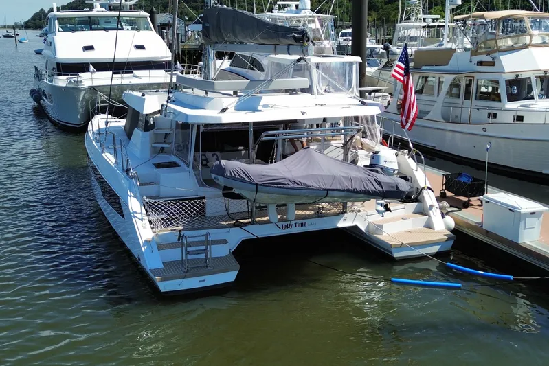 Jolly Time Yacht Photos Pics 2021 Leopard 42 catamaran docked at marina with American flag and covered dinghy.