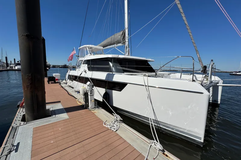 Jolly Time Yacht Photos Pics 2021 Leopard 42 catamaran docked at marina, clear blue sky, American flag displayed.