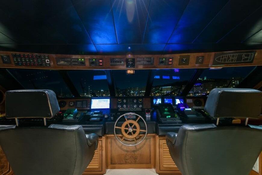 Bridge of 1991 Explorer Trawler tri deck 110' yacht with illuminated controls and city view.
