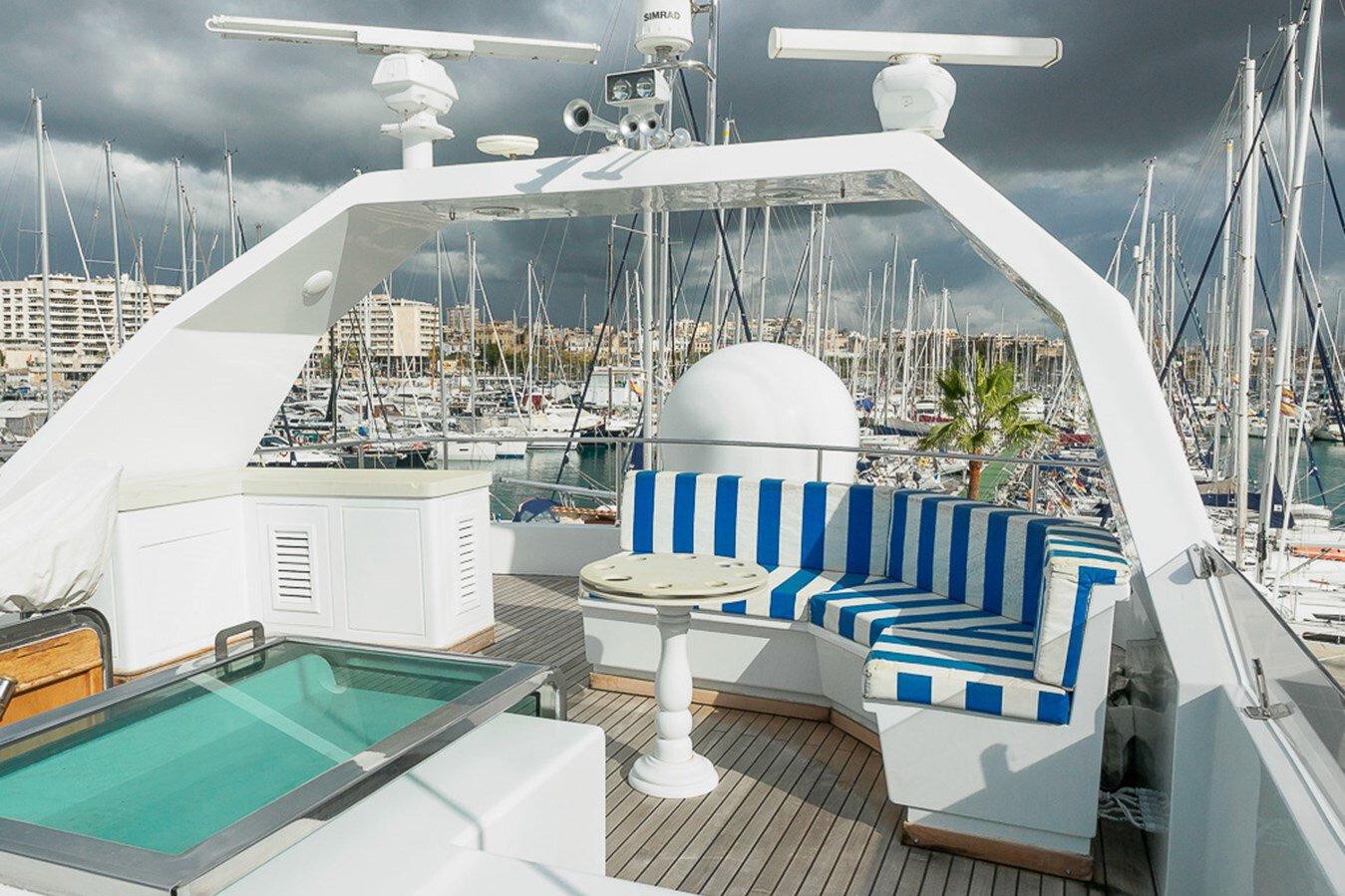 Luxurious deck of 1991 Explorer Trawler tri deck 110' with striped seating and marina view.