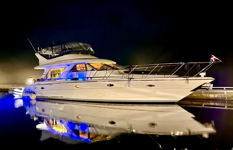  Yacht Photos Pics Luxurious Prima 5230 yacht from 1999, illuminated at night, reflecting on calm water.