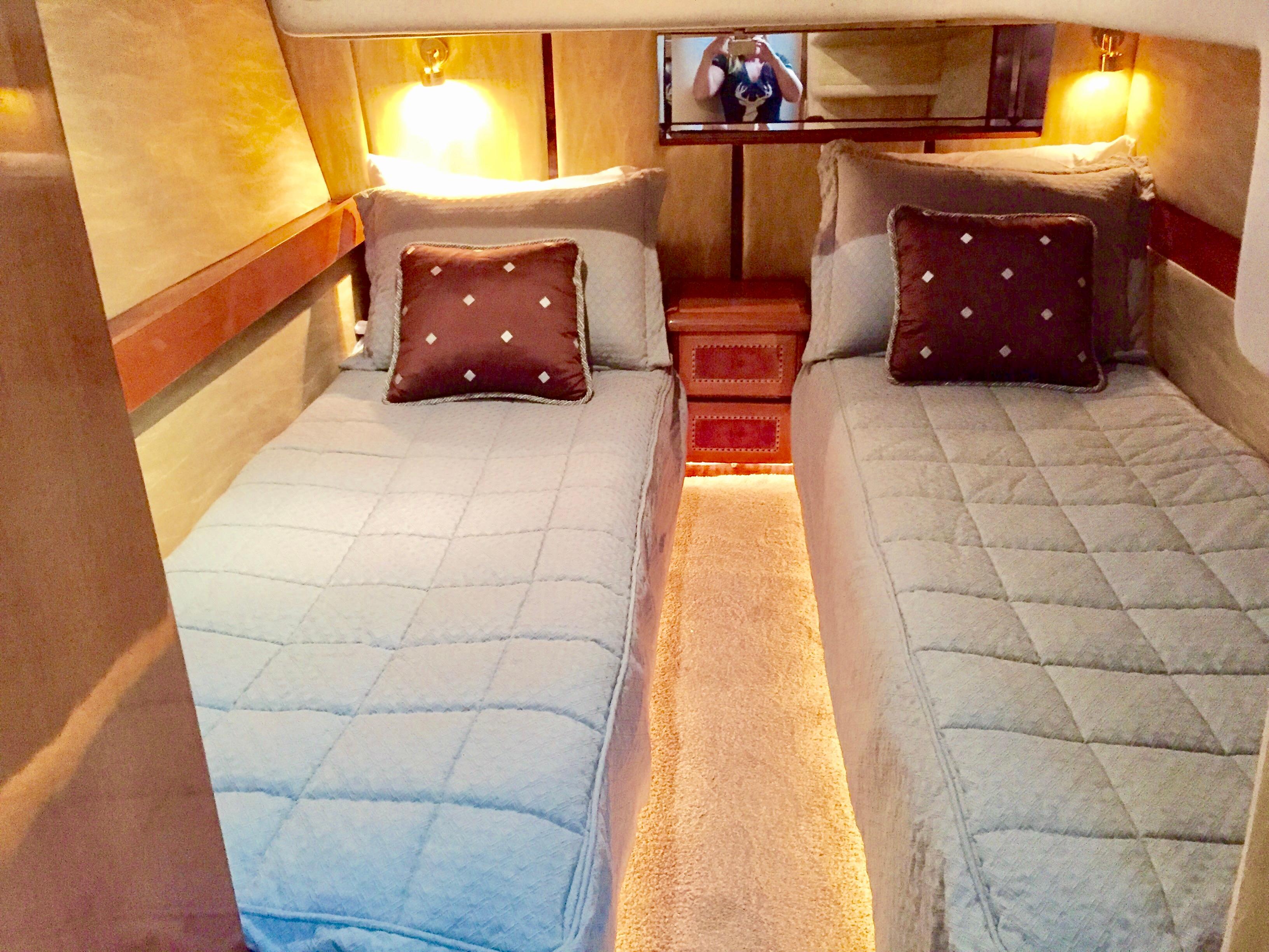 Twin beds in a 1999 Prima 5230 yacht cabin with cozy lighting.