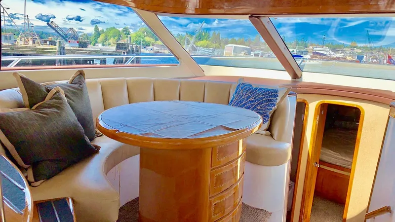 Yacht Photos Pics Luxurious Prima 5230 yacht interior with round table, plush seating, and scenic marina view.