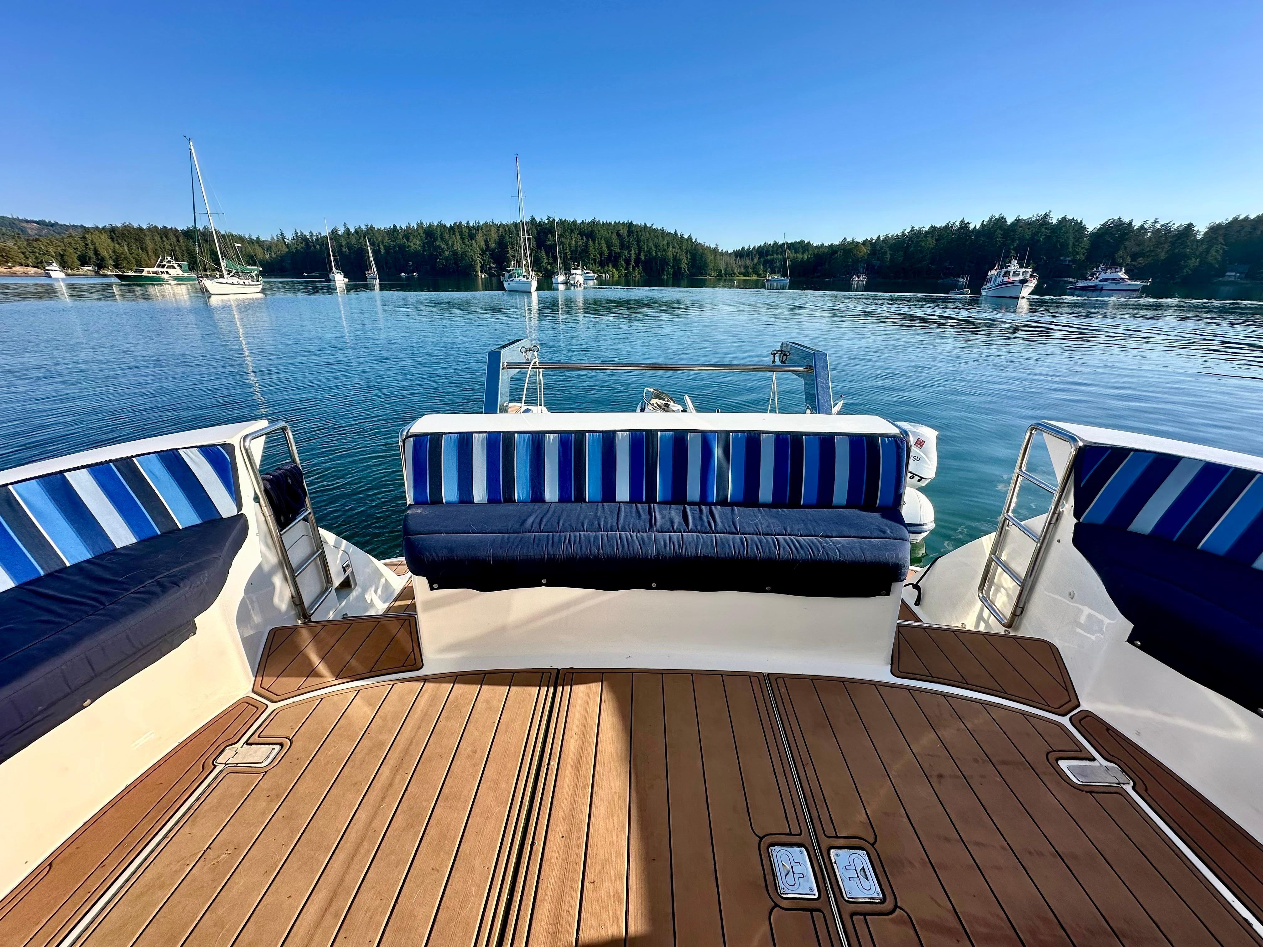 Deck view of Prima 5230 boat, 1999 model, with striped seating, overlooking a serene lake.