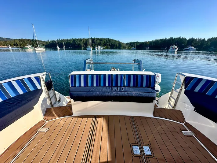  Yacht Photos Pics Deck view of Prima 5230 boat, 1999 model, with striped seating, overlooking a serene lake.
