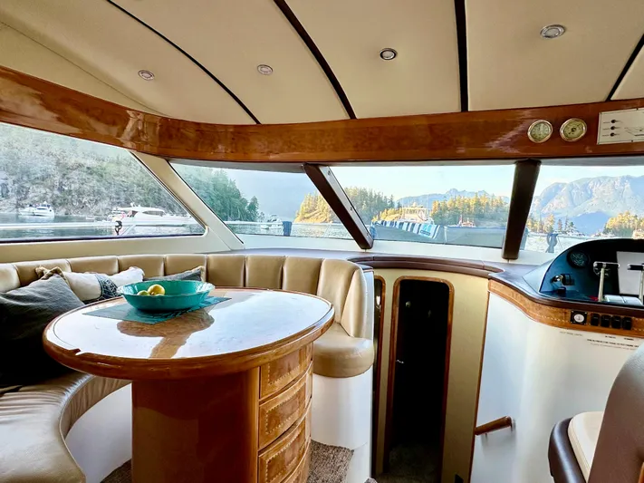 Yacht Photos Pics Luxurious Prima 5230 yacht interior with panoramic windows, wooden table, and scenic water view.