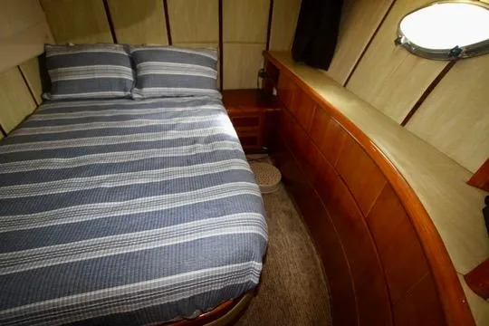  Yacht Photos Pics Cozy boat cabin with striped bedding, wooden paneling, and a small porthole window. Prima 5230, 1999.