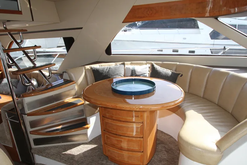  Yacht Photos Pics Luxurious yacht interior with curved seating, wooden table, and spiral staircase, Prima 5230, 1999 model.