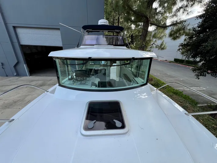  Yacht Photos Pics 2023 NJM NSB-28 boat with sleek design, docked near industrial building and trees.