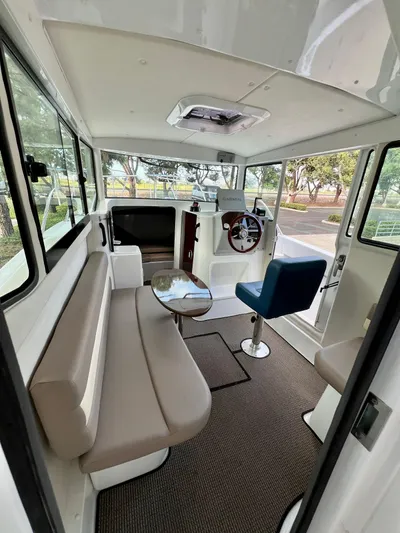  Yacht Photos Pics Interior of 2023 NJM NSB-28 boat with seating, steering wheel, and windows.