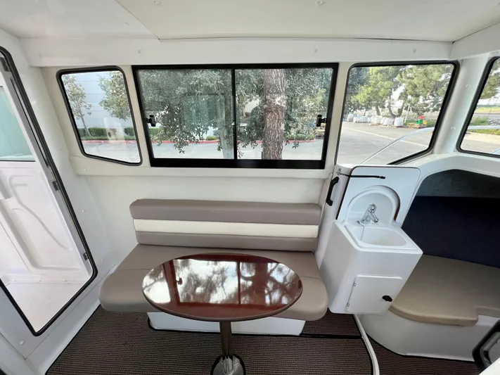  Yacht Photos Pics Interior of 2023 NJM NSB-28 boat with seating, table, and windows.
