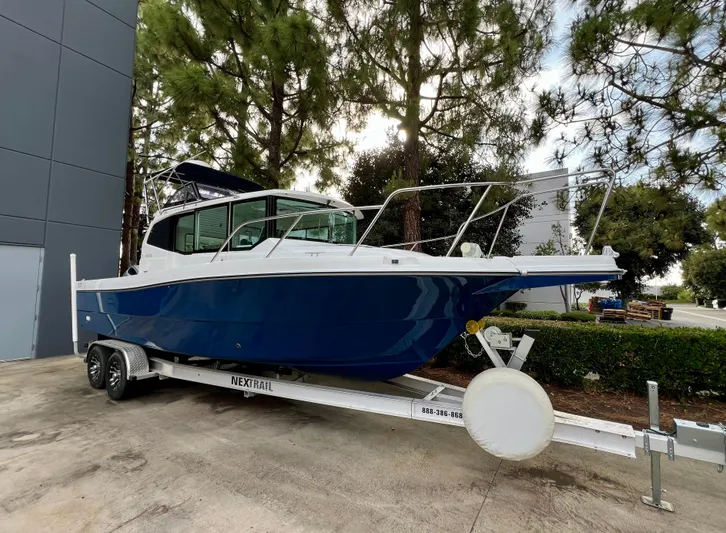  Yacht Photos Pics 2023 NJM NSB-28 boat on trailer, parked outdoors near trees and building.
