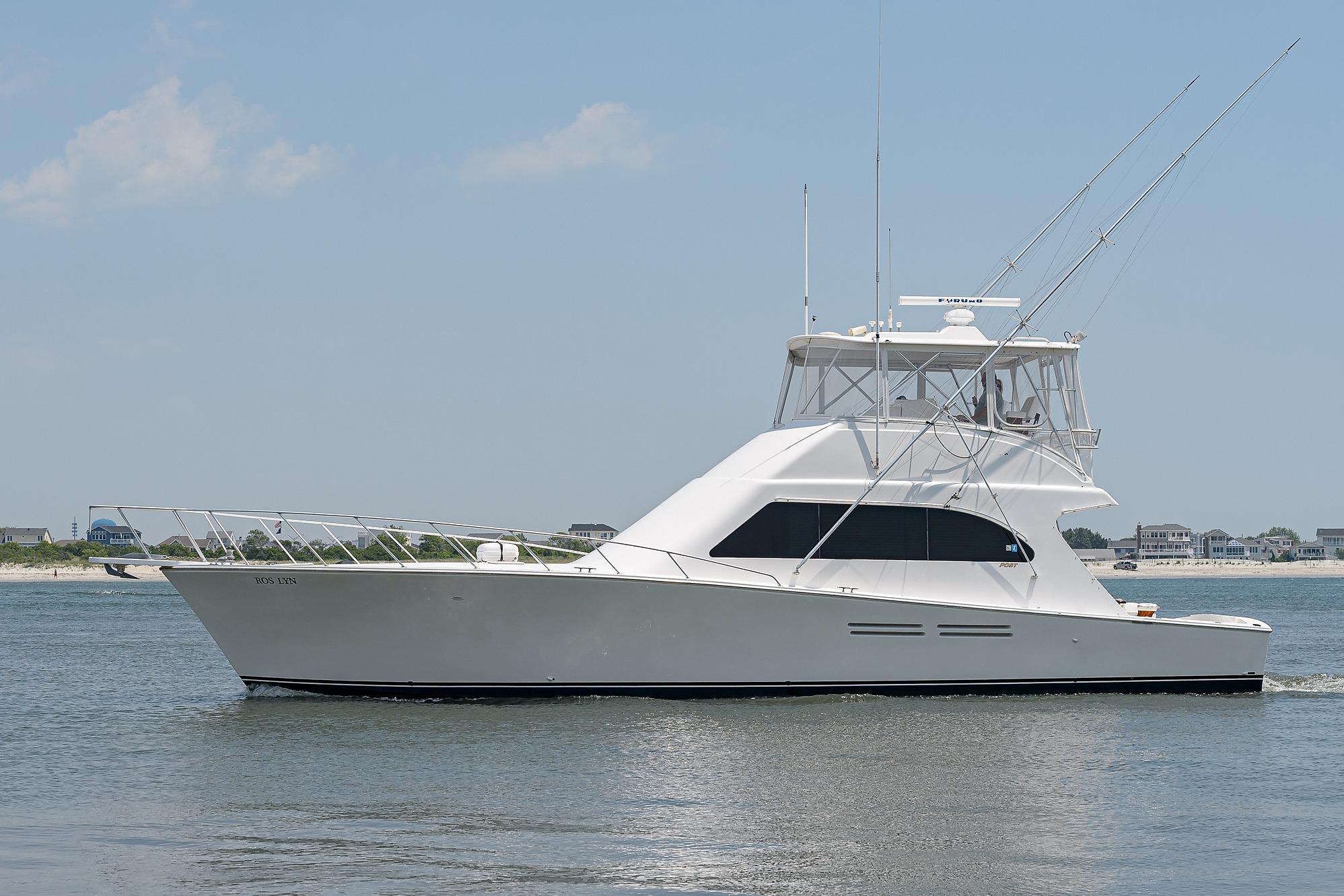2007 Post 53 Convertible yacht cruising near the shoreline on a sunny day.