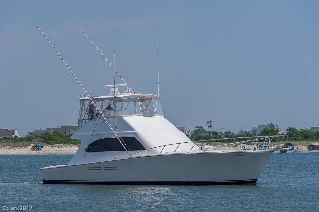 2007 Post 53 Convertible yacht cruising near a sandy beach with clear skies.
