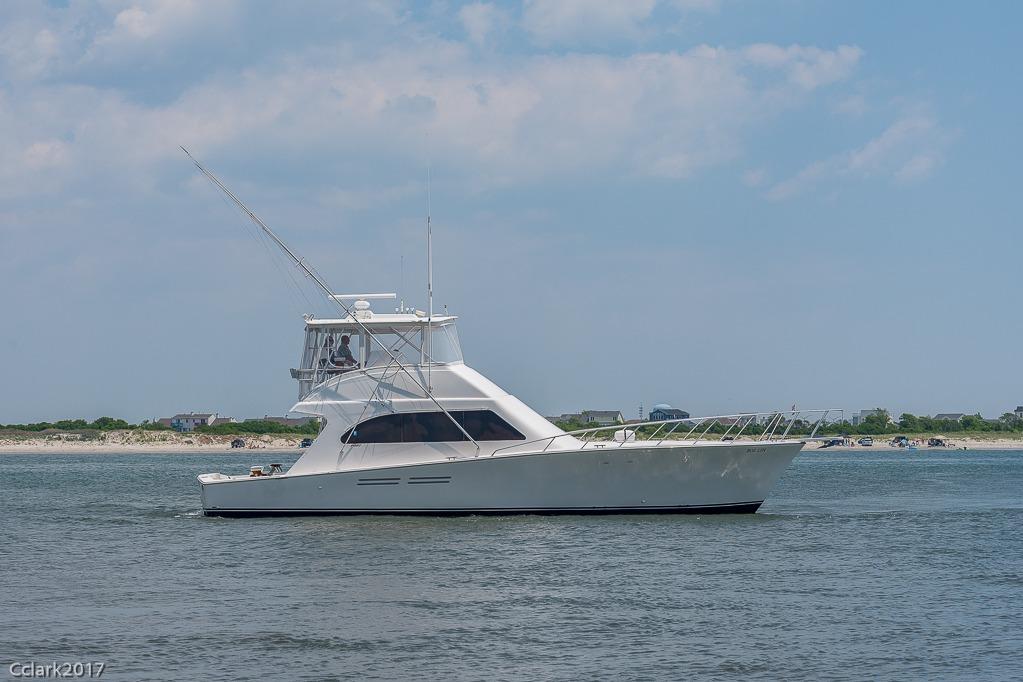 2007 Post 53 Convertible yacht cruising near the shoreline under a clear sky.