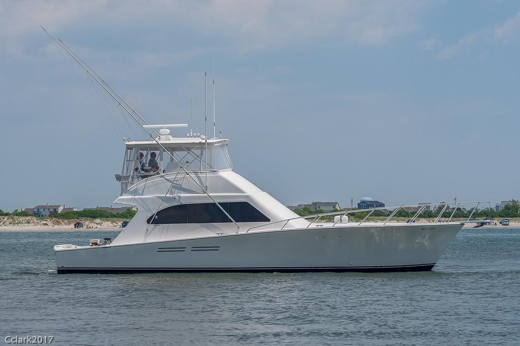 2007 Post 53 Convertible yacht cruising near shoreline under clear sky.