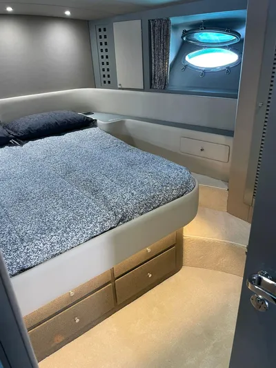  Yacht Photos Pics Interior of a 1989 Riva 51 Turborosso yacht with a cozy bedroom and porthole window.