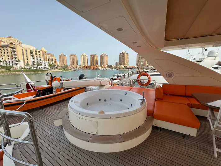 G-one Yacht Photos Pics Luxurious 2009 Azimut 82 yacht deck with jacuzzi and orange seating, overlooking marina and cityscape.