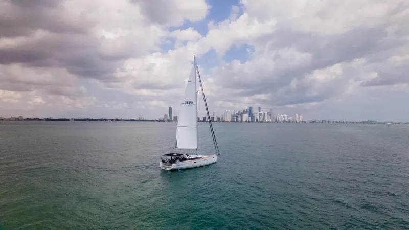 Indigo Dream Yacht Photos Pics Sailing yacht Beneteau Sense 50, 2012 model, cruising near a city skyline under cloudy skies.