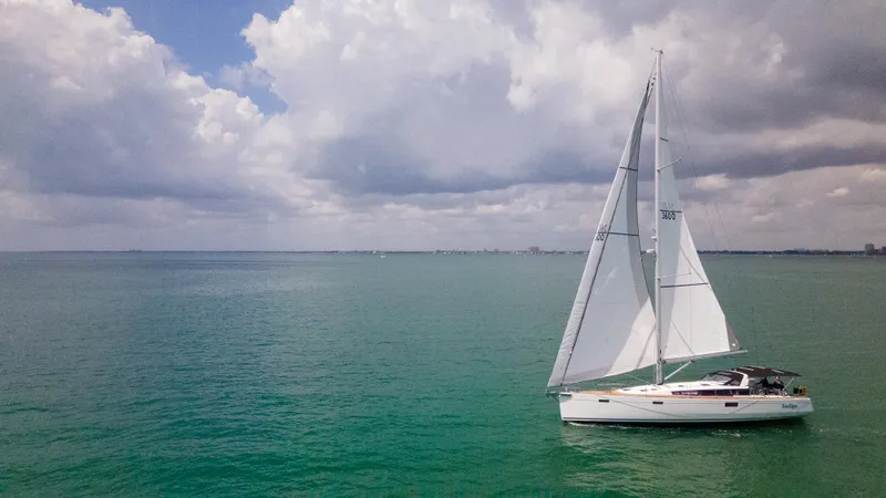 Indigo Dream Yacht Photos Pics Sailing yacht Beneteau Sense 50, 2012 model, gliding on calm turquoise waters under cloudy skies.