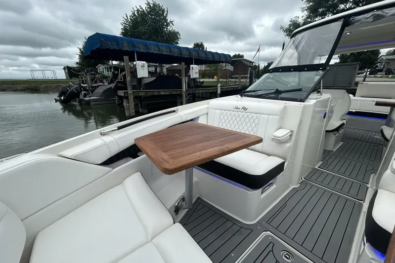  Yacht Photos Pics 2020 Sea Ray 350 SLX boat interior with white seating and wooden table, docked by the water.