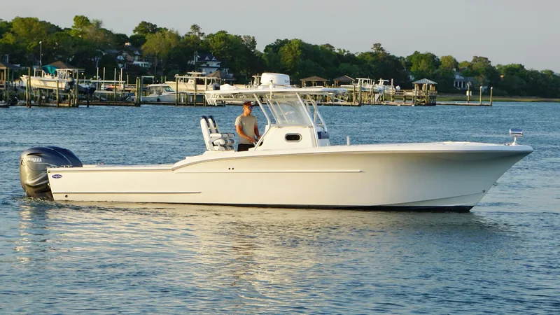  Yacht Photos Pics 2013 Buddy Davis 34 Center Console boat cruising on calm water near a marina.