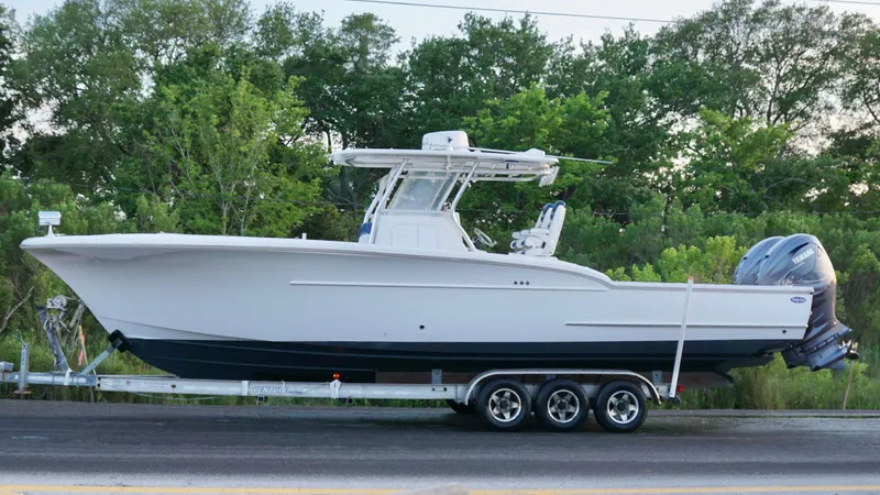  Yacht Photos Pics 2013 Buddy Davis 34 Center Console boat on a trailer, parked near lush greenery.
