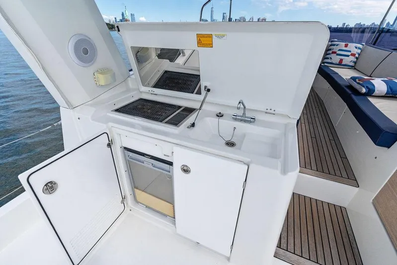 Dreamscape Yacht Photos Pics Outdoor kitchenette on 2020 Beneteau Swift Trawler 50, featuring sink and grill, with city skyline view.
