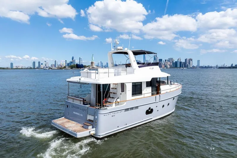 Dreamscape Yacht Photos Pics 2020 Beneteau Swift Trawler 50 cruising near city skyline under blue sky.