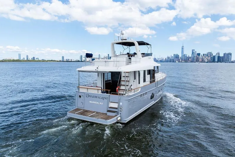 Dreamscape Yacht Photos Pics 2020 Beneteau Swift Trawler 50 cruising near city skyline under blue sky.