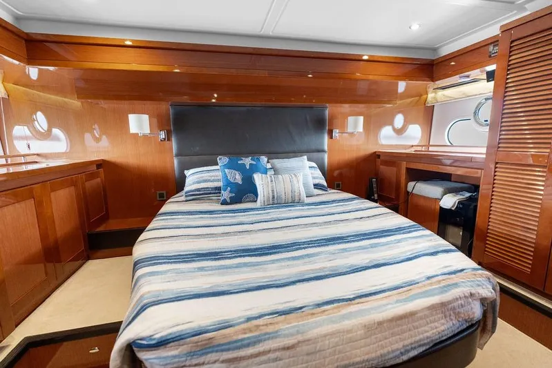Dreamscape Yacht Photos Pics Luxurious cabin interior of 2020 Beneteau Swift Trawler 50 with striped bedding and wooden finishes.