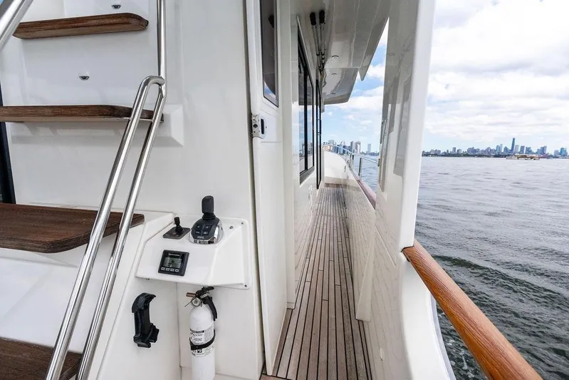 Dreamscape Yacht Photos Pics 2020 Beneteau Swift Trawler 50 deck with city skyline view, featuring wooden steps and railing.