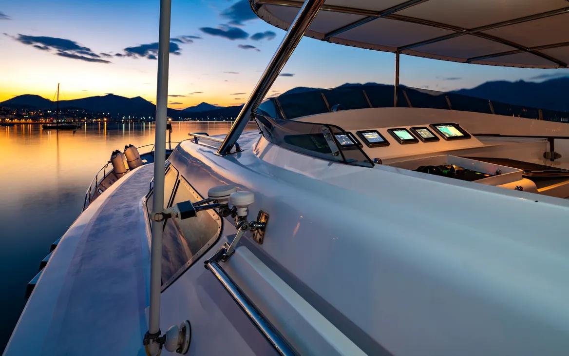 Luxury Codecasa yacht from 1987 at sunset, serene water and mountain backdrop.